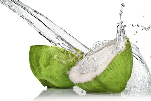 Green coconut cut in half with coconut water pouring out